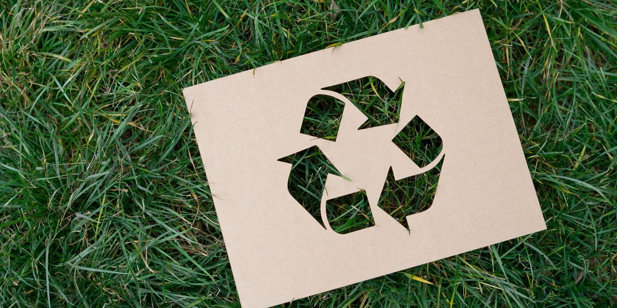 Recycle icon on a wooden board on the grass